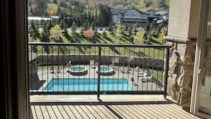 A balcony with a pool, stone walls, and a view of a hilly landscape. - Luxury Windham Mtn Slope Side 3 BDRM Condo (Windham)