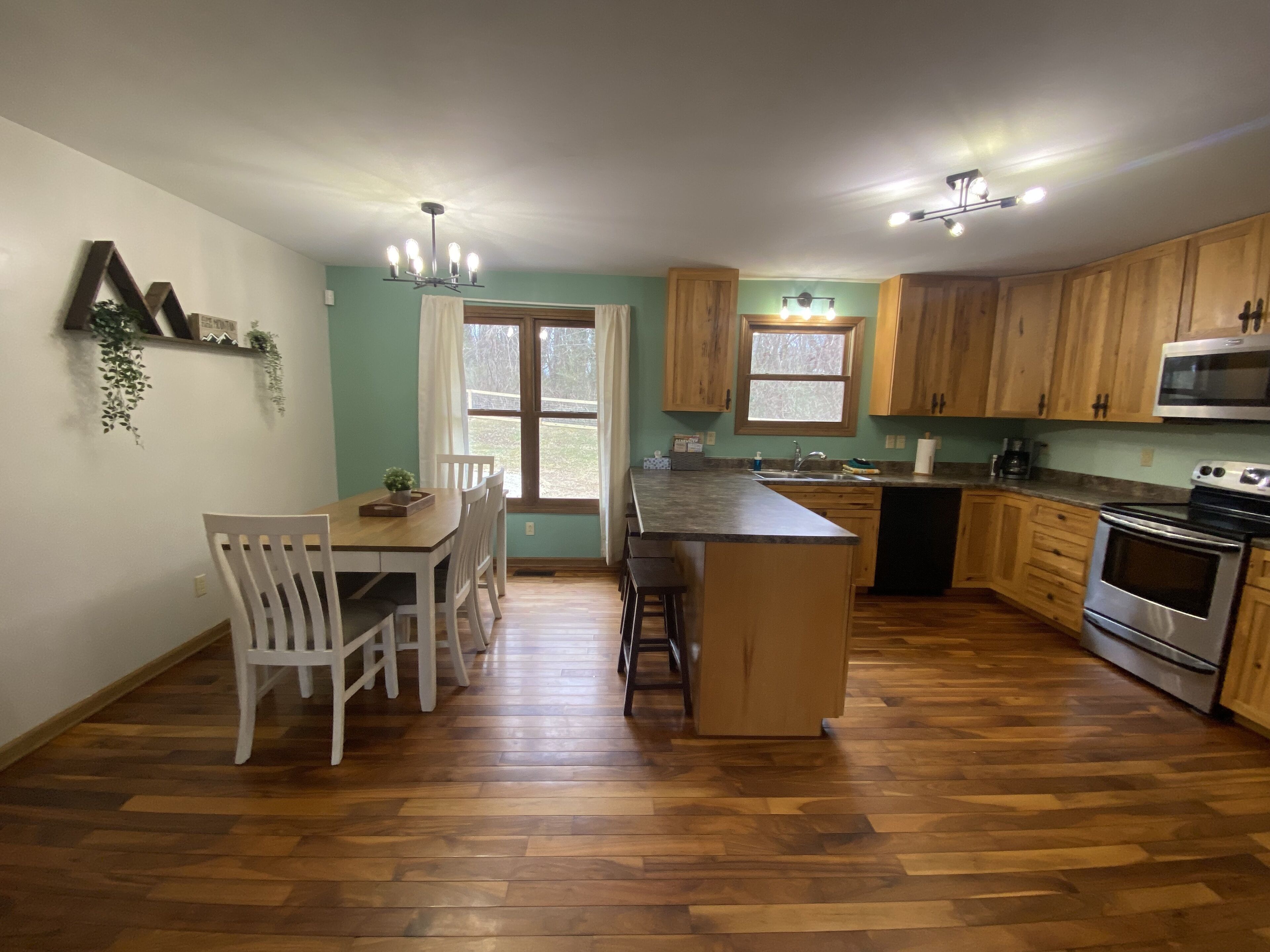Une cuisine avec des meubles en bois, un îlot central et un coin repas avec des chaises.