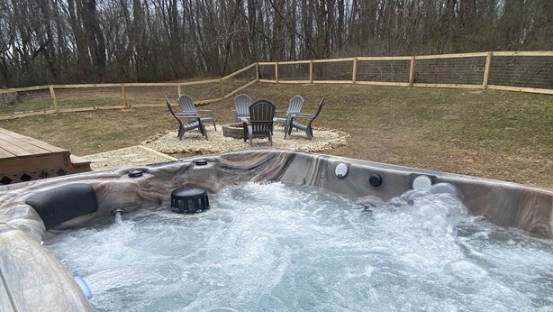 A hot tub with a wooden deck and chairs in the background.