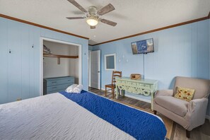 A bedroom with a bed, a desk, a chair, a wardrobe, and a ceiling fan.