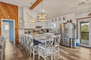 A modern kitchen with white cabinetry, a central island, and stainless steel appliances. - Sandpiper Paradise | 630 ft to the beach | Private Pool (Virginia Beach)