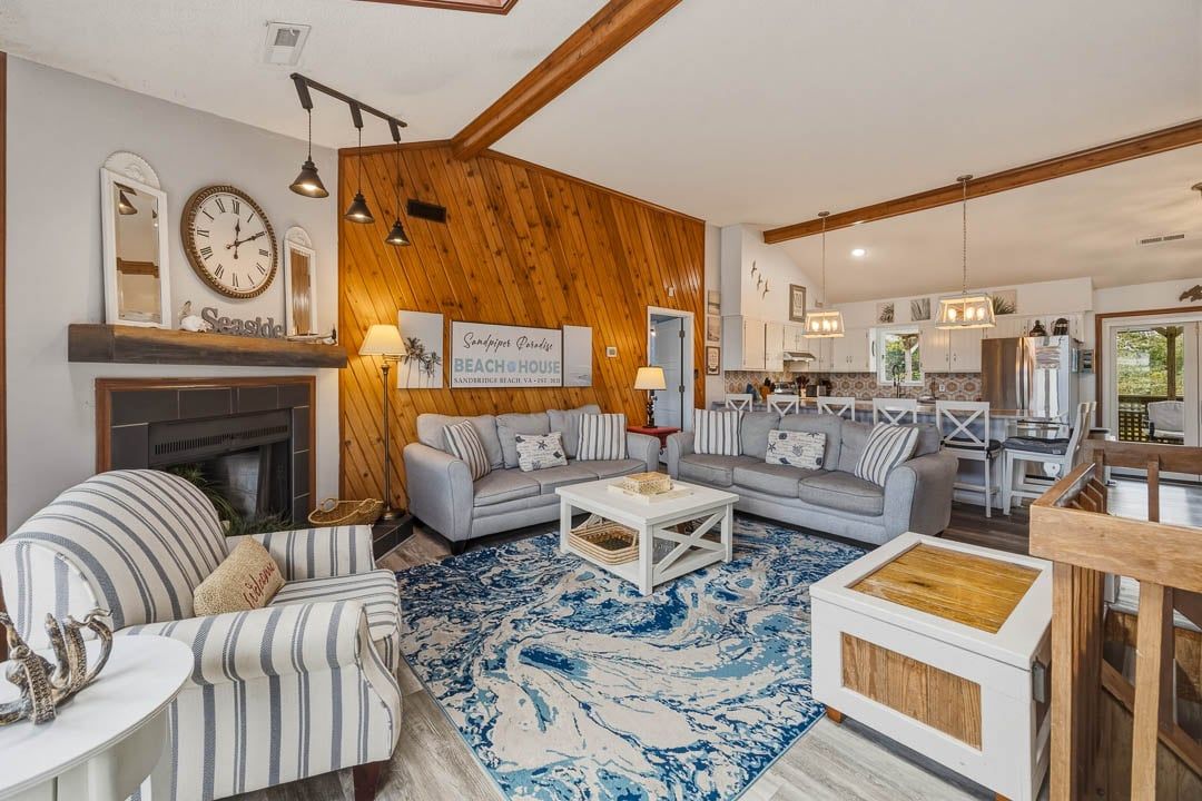 A living room with a fireplace, two sofas, a coffee table, and a blue patterned rug.