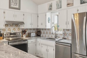 A kitchen with white cabinets, stainless steel appliances, and a patterned backsplash.