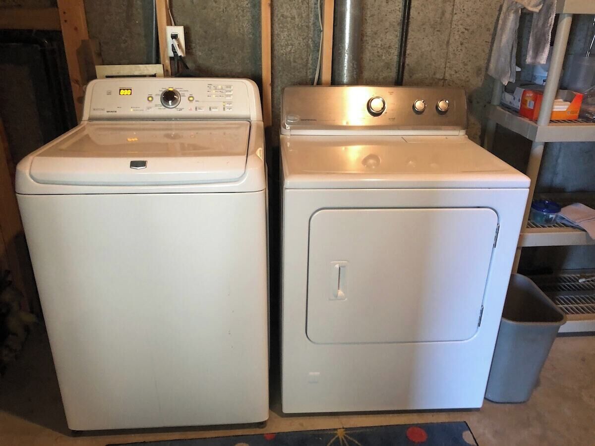 Une buanderie équipée d’un lave-linge à chargement frontal et d’un sèche-linge superposé.