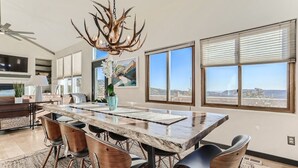 A spacious dining area with a large wooden table, modern chairs, and a unique antler chandelier. - Cozy Mountain Escape | Hot Tub +Views | Dog Friendly | Sleeps 10 | 45 min Denver (Evergreen)