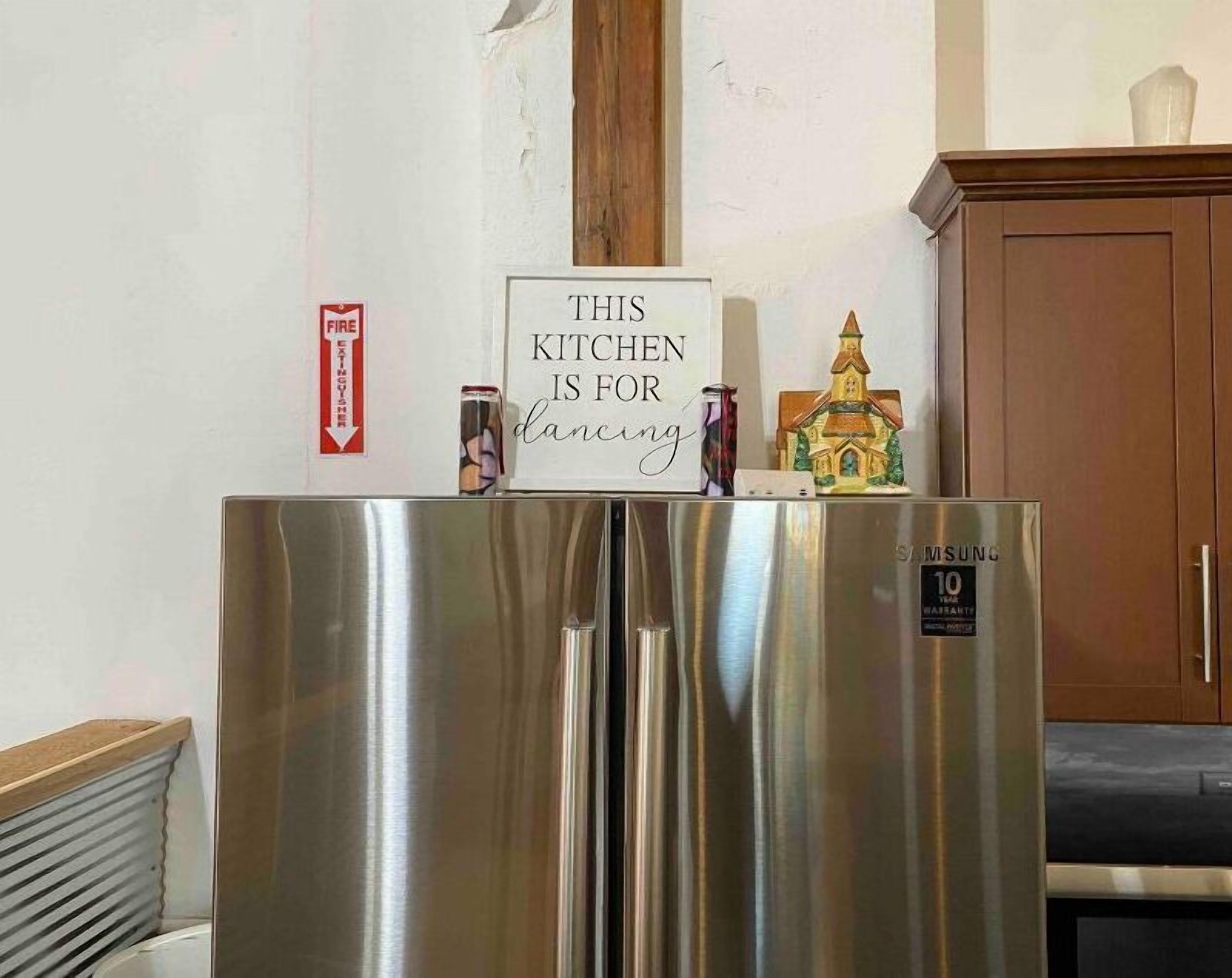 Un refrigerador de acero inoxidable con un cartel en la parte superior que dice "ESTA COCINA es para bailar."