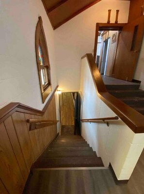 A wooden staircase with a handrail, a small window, and a door at the top.
