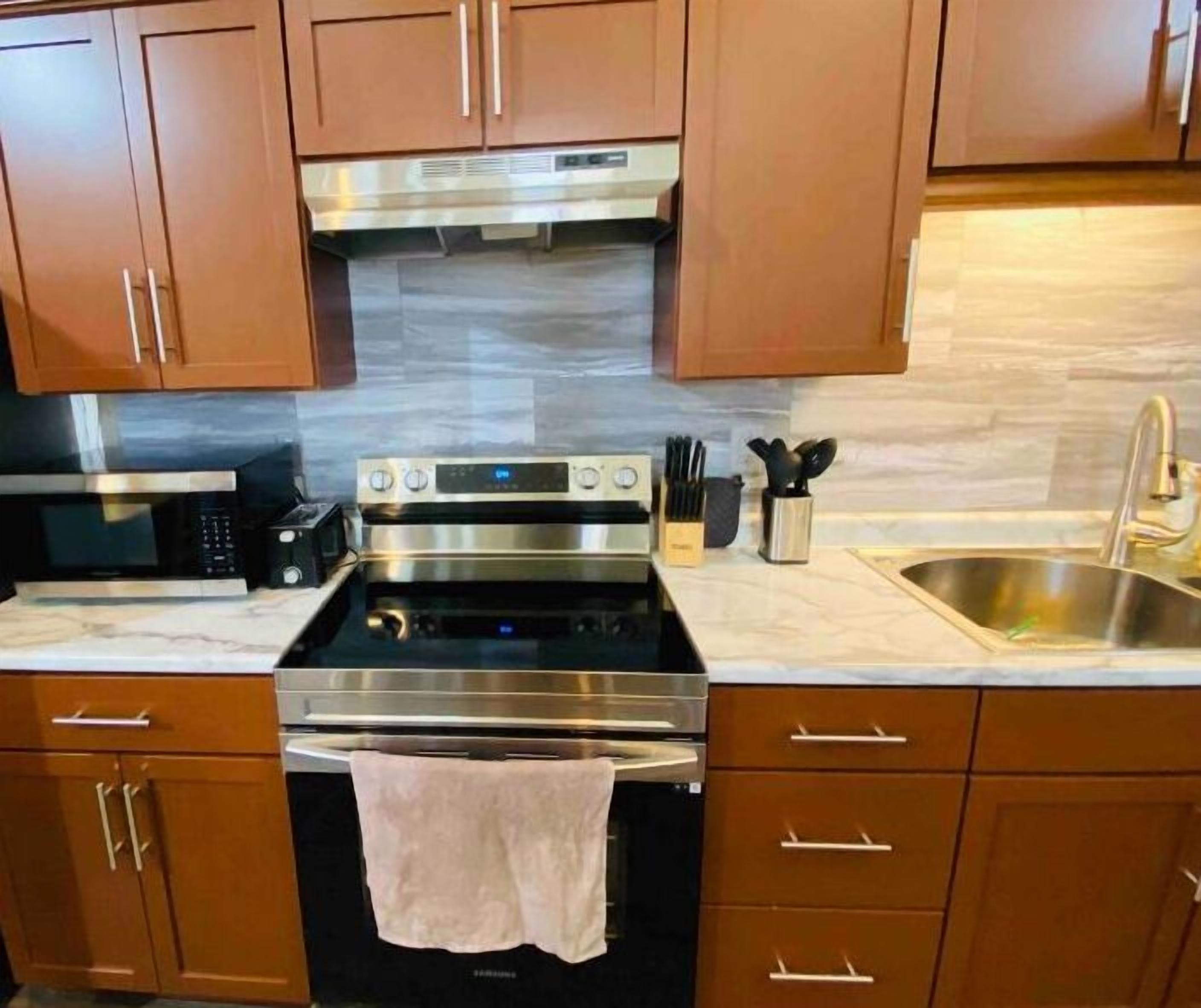A kitchen with wooden cabinets, a stainless steel oven, a microwave, and a sink.