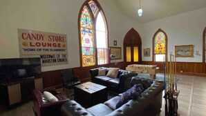 Innenansicht einer Kirche mit einer Lounge, einem Süßwarenladen-Schild und Buntglasfenstern.