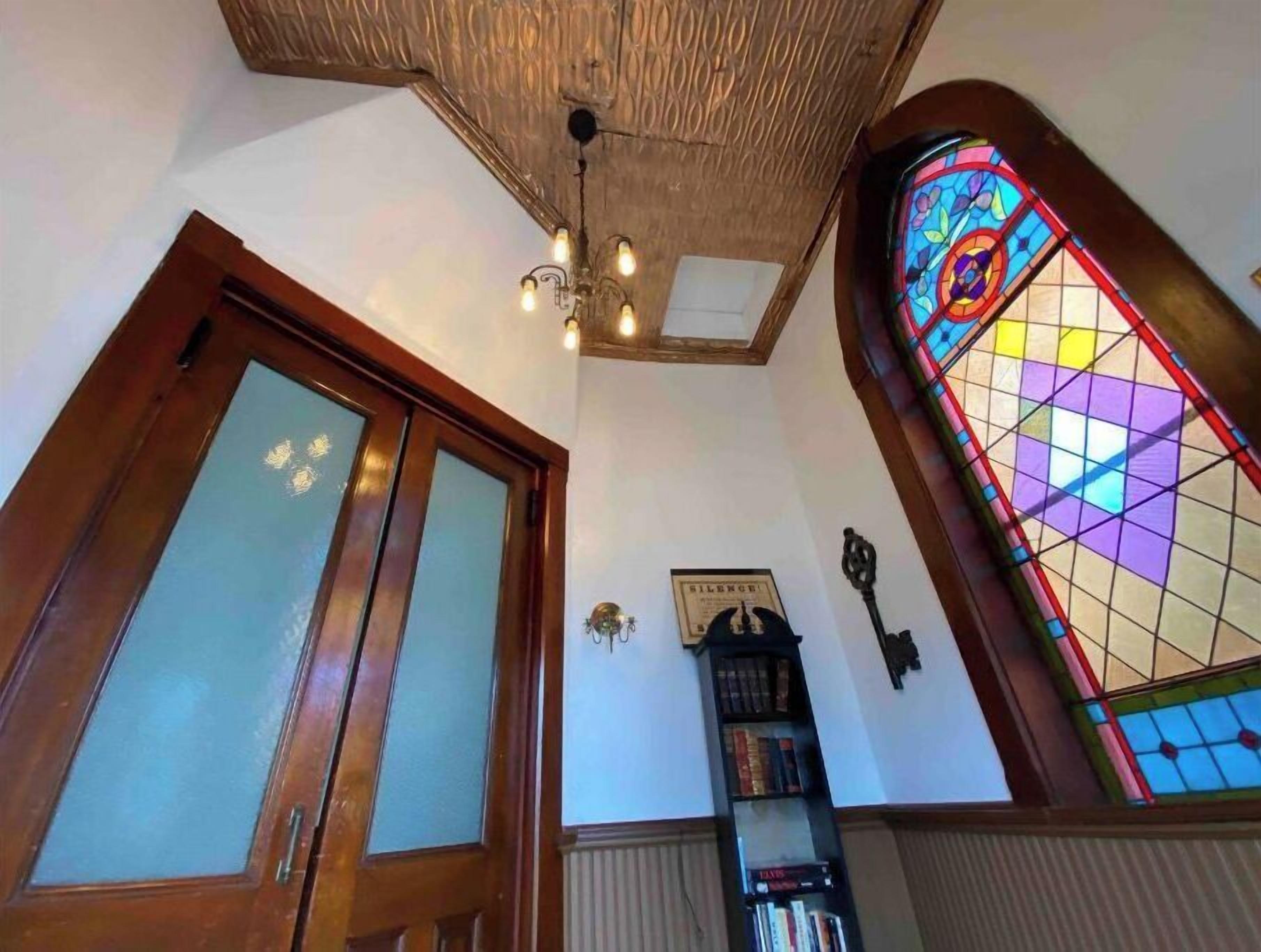 A room with a wooden door, a stained glass window, and a ceiling with a light fixture.