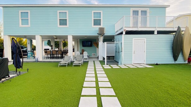 A two-story light blue house with a covered patio area, a pool, and a stone pathway leading to the entrance. - 3-bedroom house in Lower Keys with Hot Tub, Sleeps 10+, Pet Freindly (Big Pine Key)