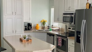 A modern kitchen with white cabinetry, a stainless steel refrigerator, an oven, a microwave, and a coffee maker. - 3-bedroom house in Lower Keys with Hot Tub, Sleeps 10+, Pet Freindly (Big Pine Key)