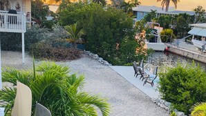 A view of a resort with a pool area, palm trees, and a sunset in the background. - 3-bedroom house in Lower Keys with Hot Tub, Sleeps 10+, Pet Freindly (Big Pine Key)