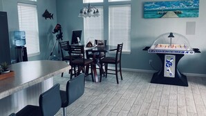 A kitchen with a dining table, chairs, a water dispenser, a tripod, and a foosball table. - 3-bedroom house in Lower Keys with Hot Tub, Sleeps 10+, Pet Freindly (Big Pine Key)
