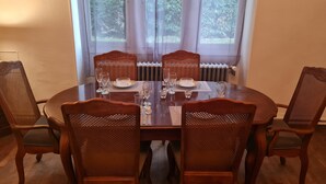 A dining table set for four with chairs, a window with curtains, and a radiator. - Cosy Cottage with pool in the countryside, France (Persac)