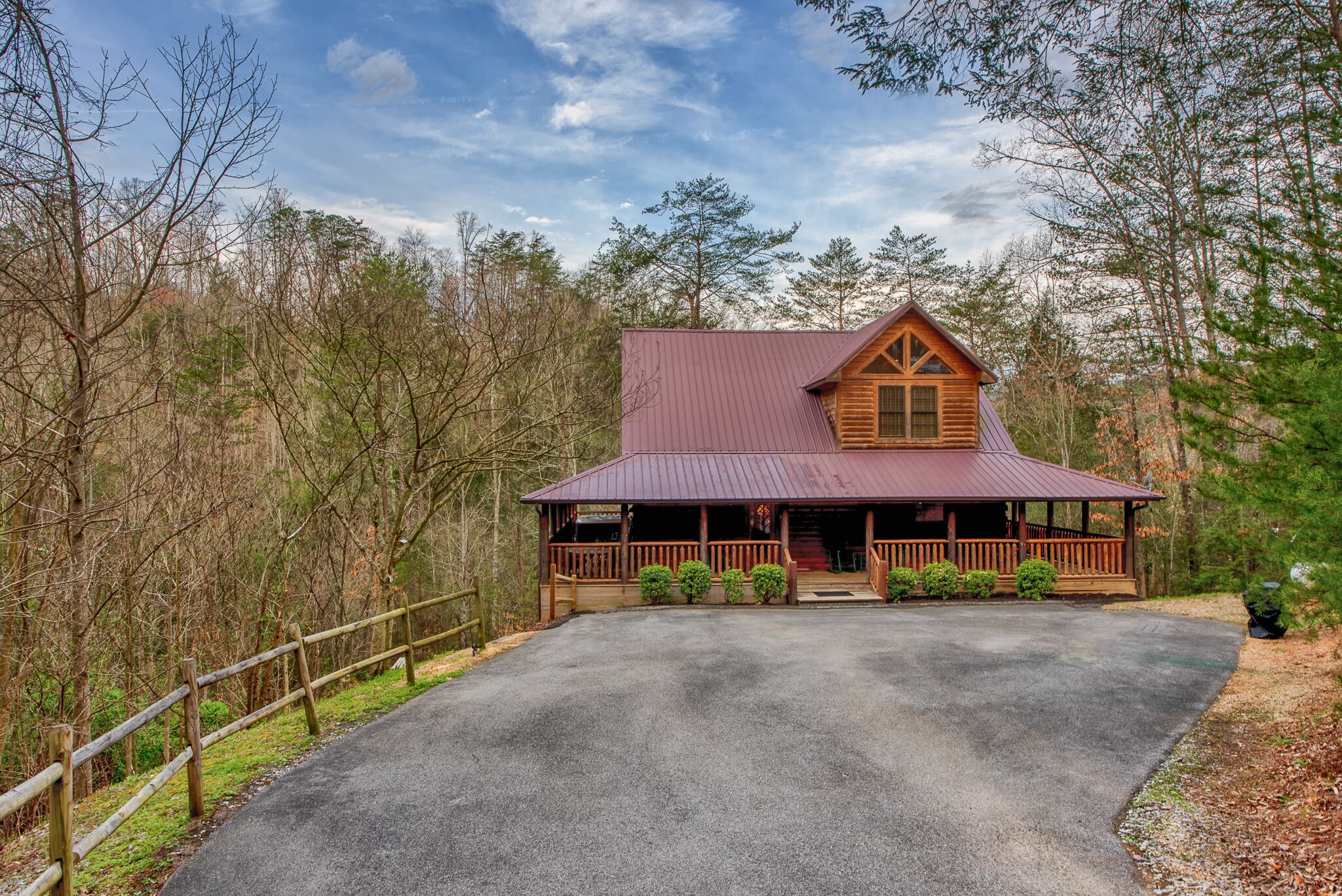 A cabin with a metal roof, wooden exterior, and a porch with railings.