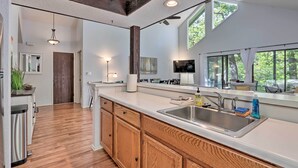 Una cocina moderna con armarios de madera, un lavamanos de acero inoxidable y un amplio ventanal que proporciona luz natural.