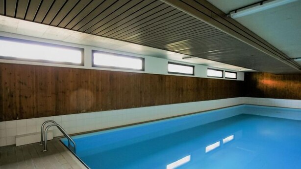 Una piscina interior con pared de madera y suelo de baldosas.