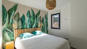 Ein Schlafzimmer mit einem großen Bett, einem Holz-Kopfteil und einer Wandmalerei von grünen Blättern.