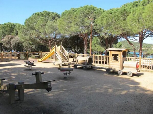 A playground with a slide, swings, and a small train.