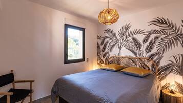 Una camera da letto con un letto, una finestra, un murale, una sedia e una lampada.
