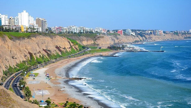 Un paisaje costero con playa, acantilados y un faro.