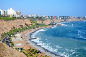 A coastal cityscape with a beach, cliffs, and a lighthouse. - Charming & Luxury Condo (Miraflores)