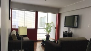 Una sala de estar con dos sofás, un televisor, una lámpara y una planta.