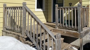 A yellow house with a wooden porch and a number 106 sign. - Gateway to the Keweenaw  (Allouez)