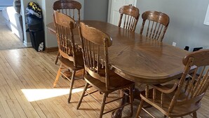A dining area with a wooden table and six chairs, a white door, and a hallway leading to a bedroom. - Gateway to the Keweenaw  (Allouez)