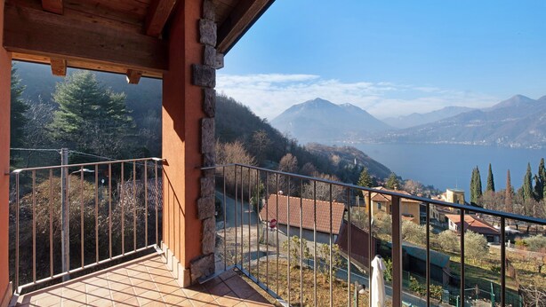 Un balcon avec vue sur les montagnes et un lac.