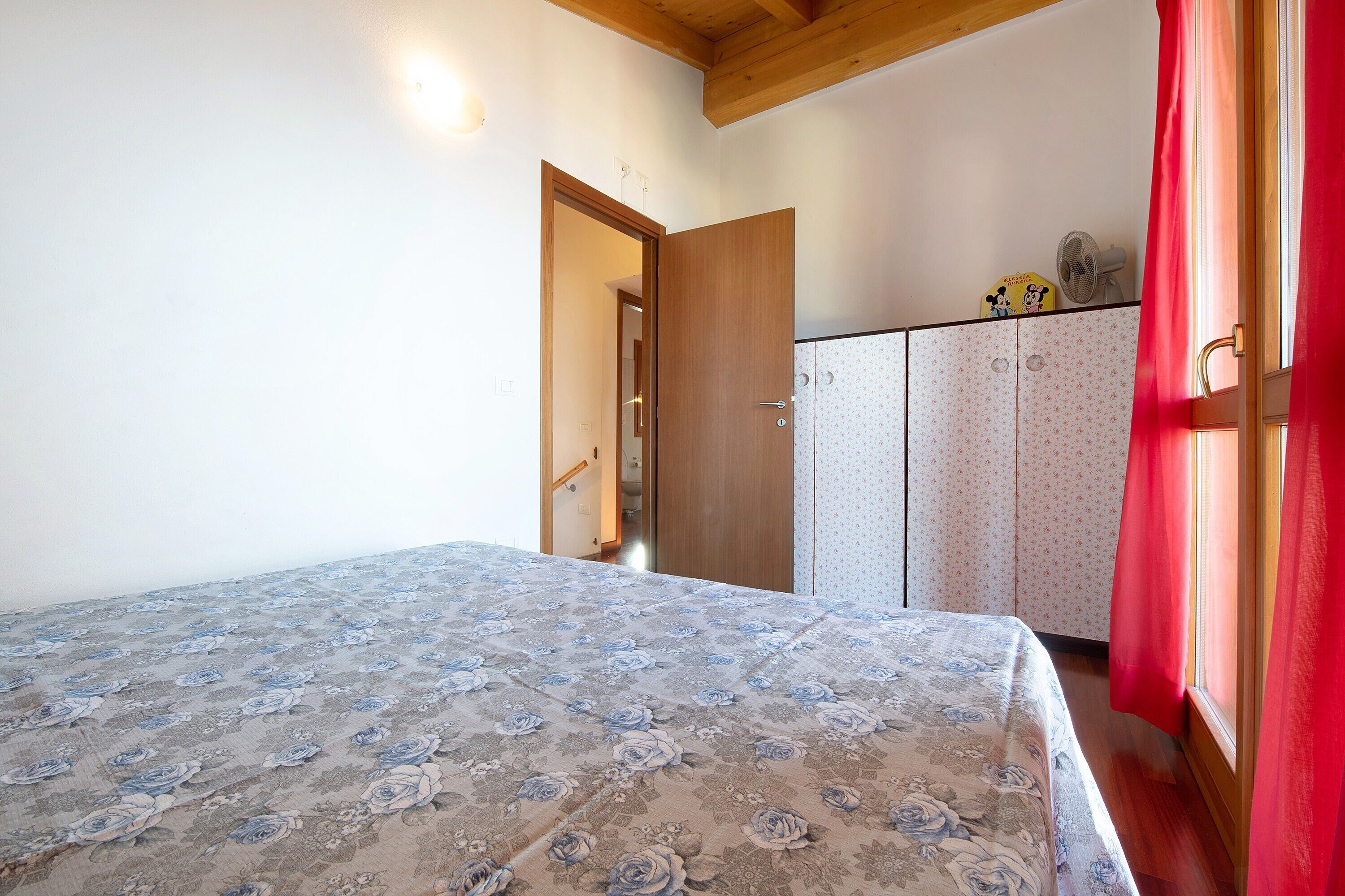 Un dormitorio con cama, armario y puerta que da a otra habitación.