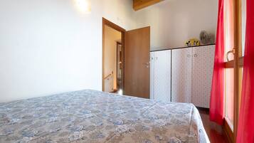 Un dormitorio con cama, armario y puerta que da a otra habitación.