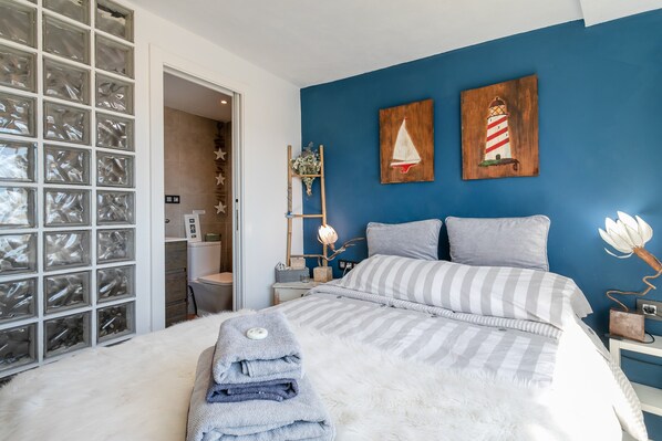 Un dormitorio con cama, mesita de noche, lámpara y obra de arte en la pared.