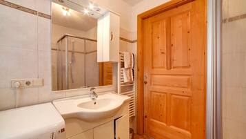 Une salle de bain avec un lavabo, un miroir et une porte en bois.