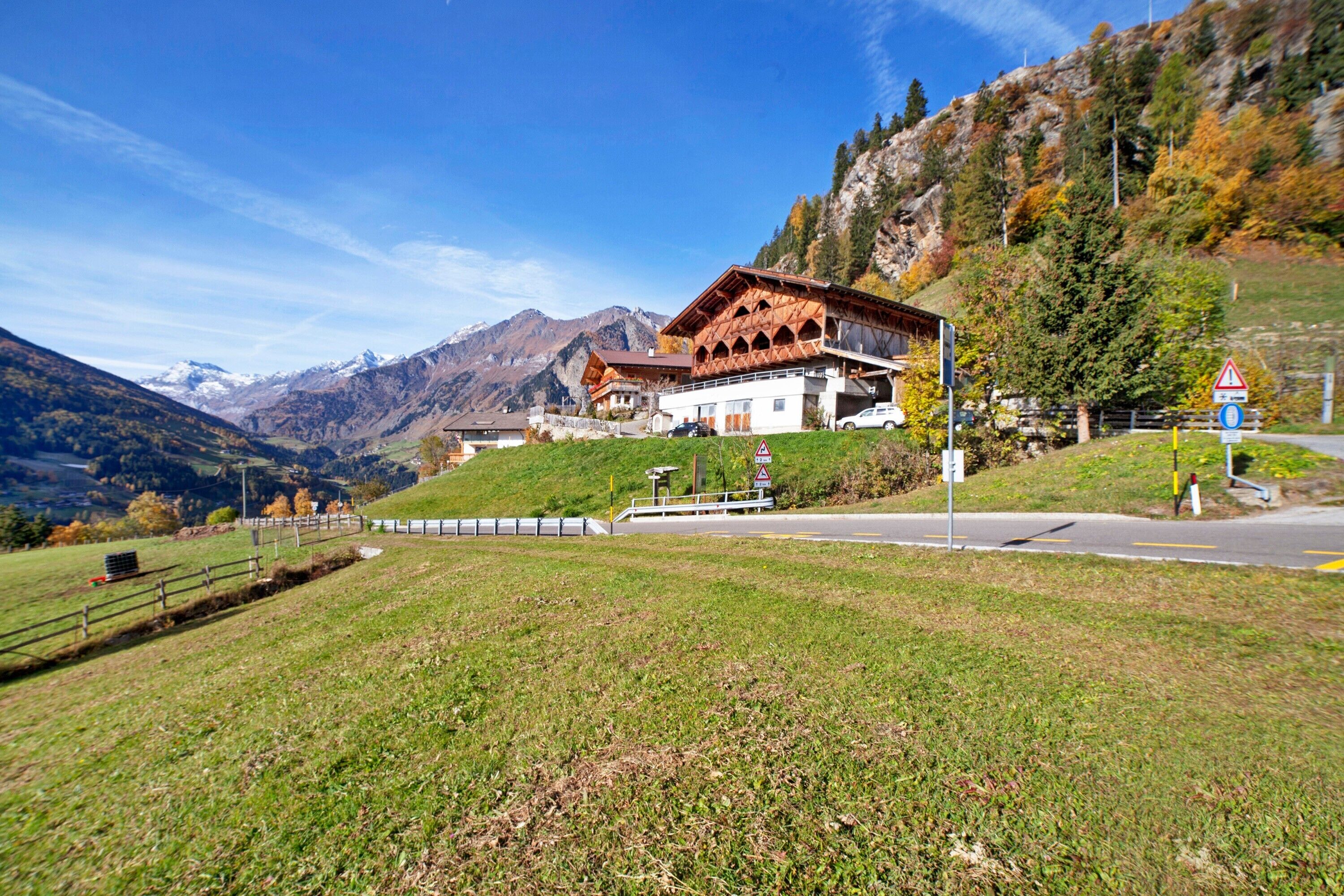 A mountain lodge with a wooden facade, a paved driveway, and a view of the surrounding mountains.