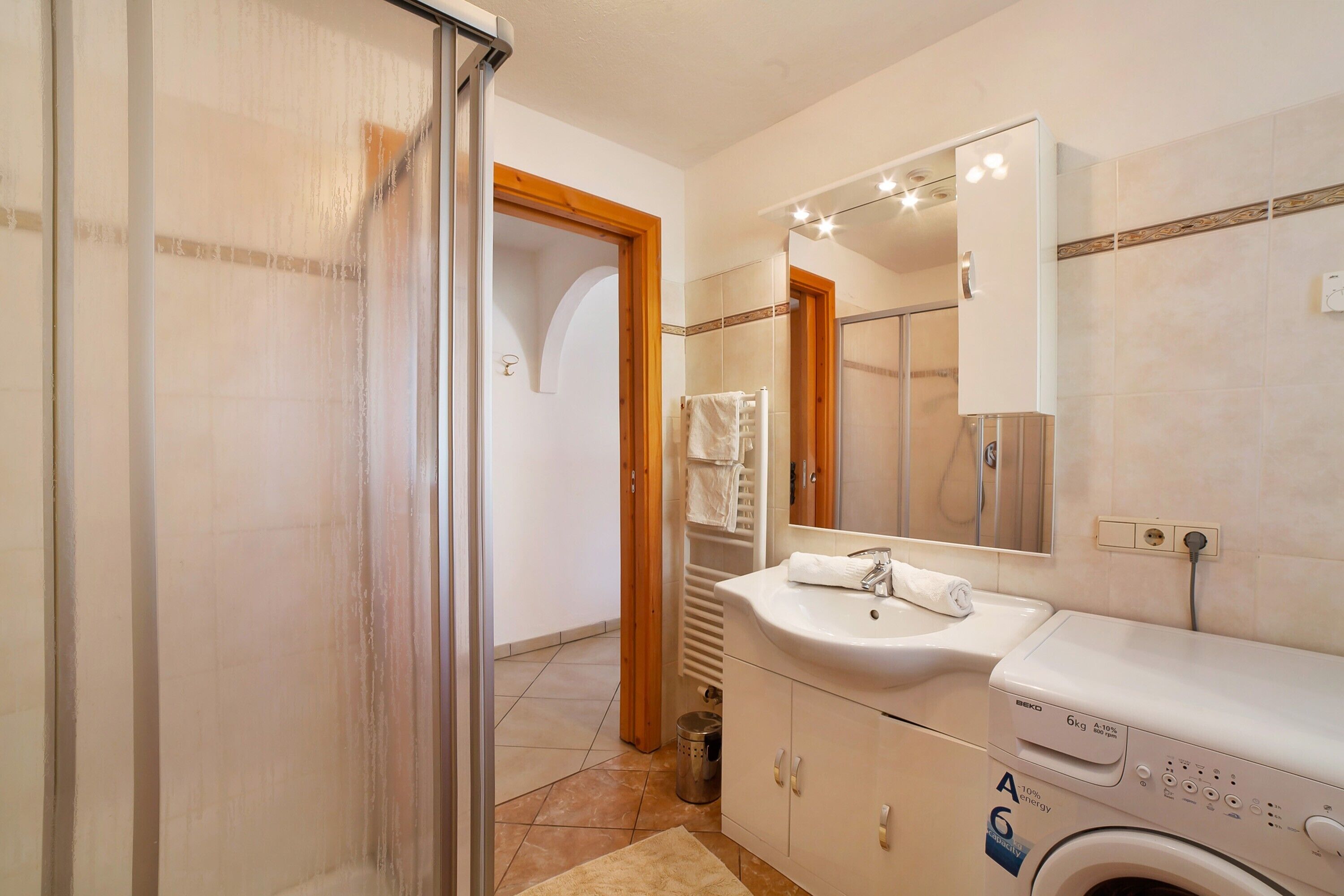 A bathroom with a shower, sink, and washing machine.