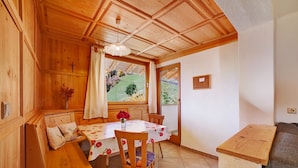 A wooden interior with a dining table, bench seating, and a view of the outdoors.
