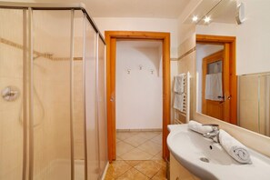 Une salle de bain avec une douche à parois de verre, un lavabo avec un miroir et un porte-serviettes.