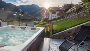 A hot tub with a view of a mountainous landscape and a wooden deck.