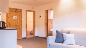 A room with a wooden door, a sofa, and a small table. - Apartment 'Cesa Sassela' with Mountain View, Sauna, Pool, Garden, Balcony & Wi-Fi (Ortisei)