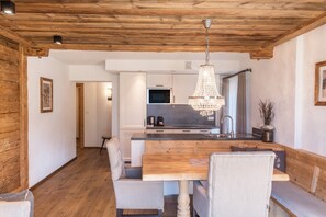 Eine moderne Küche mit Holzbalkendecke, einem Chandelier und einem Essbereich mit Holztisch und Stühlen.