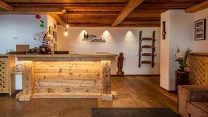 A wooden reception desk with a sign above it, a wooden ladder, and a statue on the wall. - Apartment 'Cesa Sassela Relax' with Mountain View, Sauna, Pool, Garden, Balcony & Wi-Fi (Ortisei)