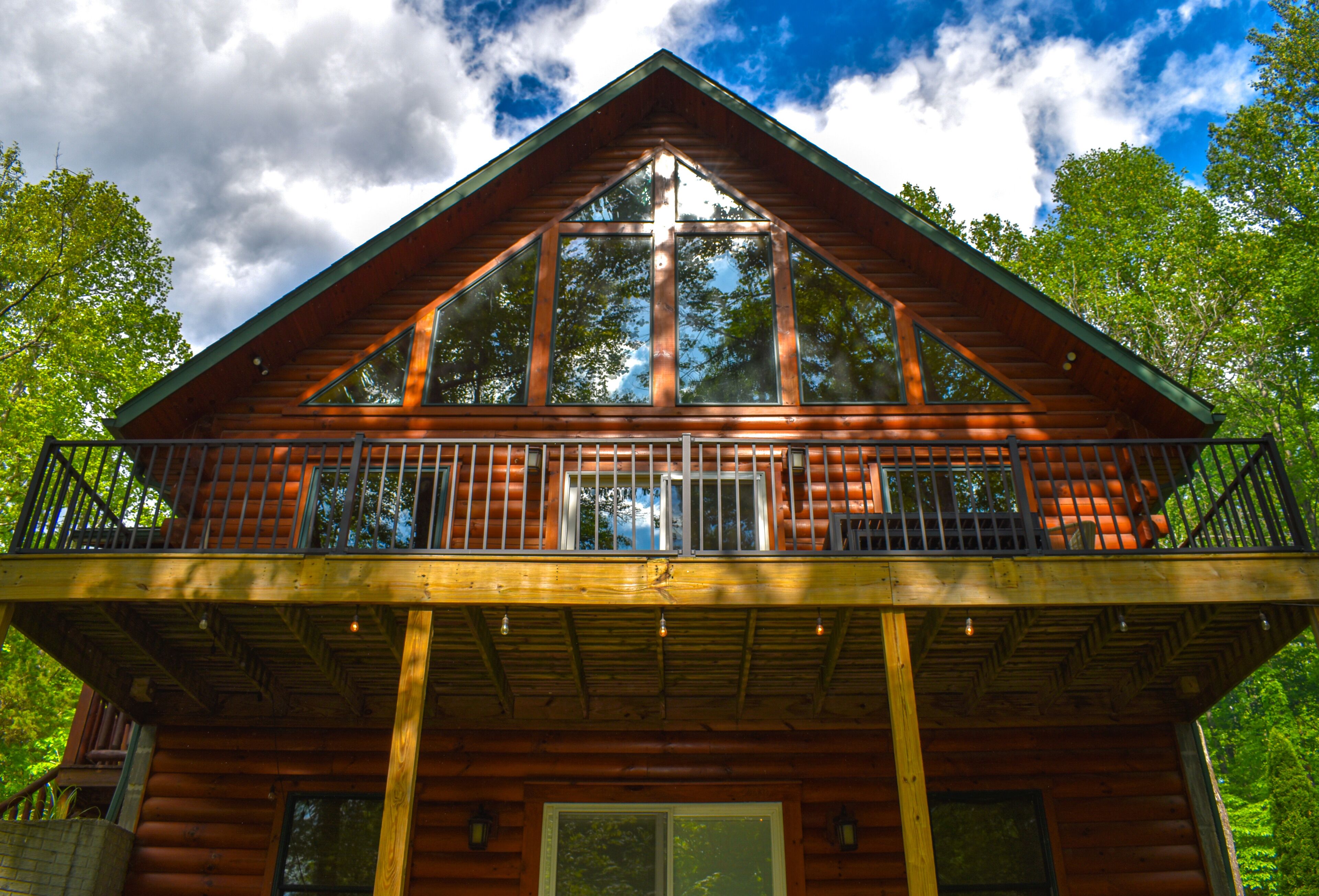 A wooden cabin with a balcony, large windows, and a steep roof.