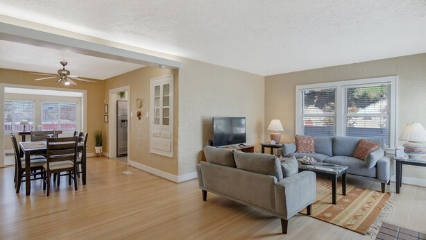 A spacious living room with a dining area, a gray sofa, and a TV.
