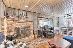Cozy living room with a stone fireplace, comfortable seating area, and dining space.