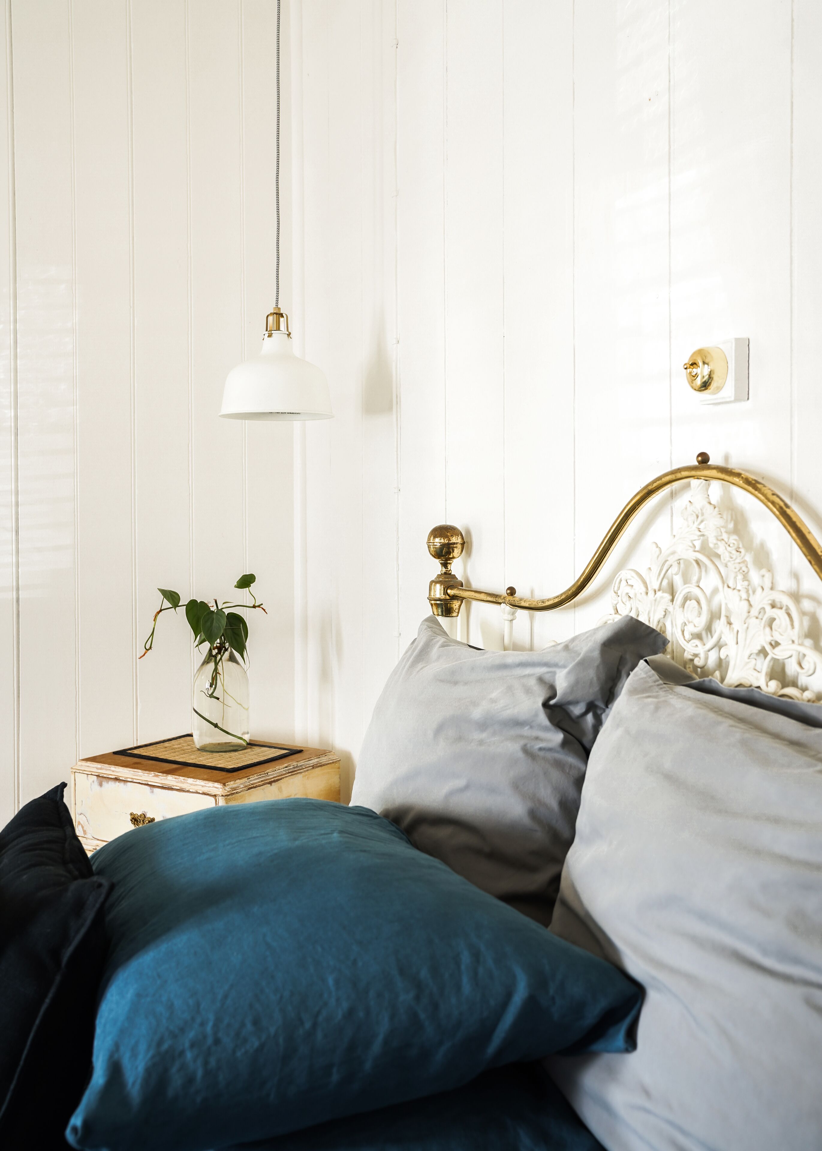 A bedroom with a bed, a bedside table with a lamp, and a decorative wall panel.