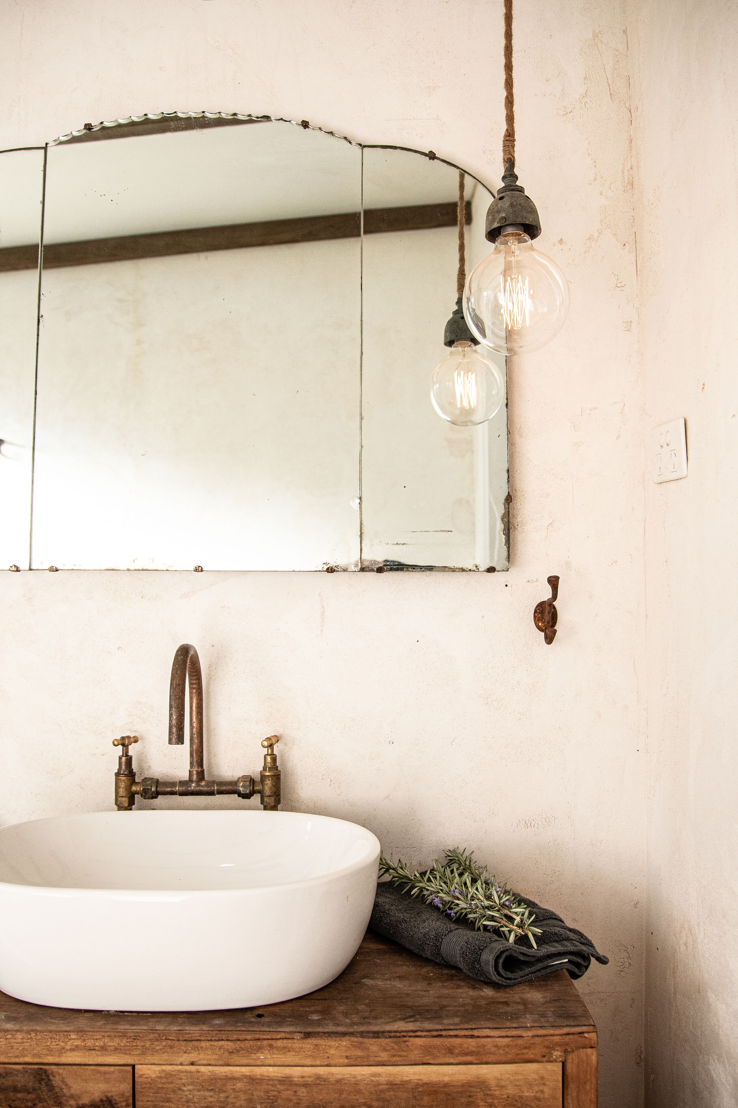 Ein Badezimmer mit Waschbecken, Spiegel und einer Pendelleuchte.