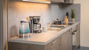 Une cuisine moderne équipée d’une machine à café, d’une bouilloire et d’un évier.