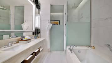 A modern bathroom with a large mirror, two sinks, a bathtub, and a glass-enclosed shower.